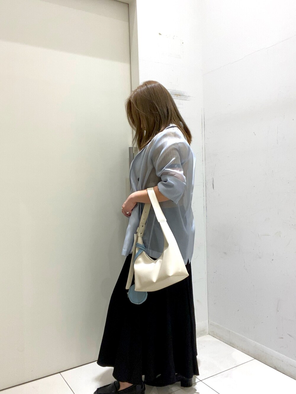 ベージュ系のニット/セーター、ブルー系のテーラードジャケット、ベージュ系のハンドバッグを着用したレディースの春コーディネートの2枚目の写真