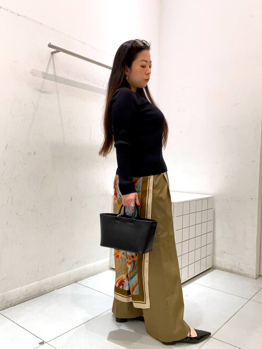 ブラック系のニット/セーター、ベージュ系のその他パンツ、ブラック系のトートバッグを着用したレディースの冬コーディネートの2枚目の写真