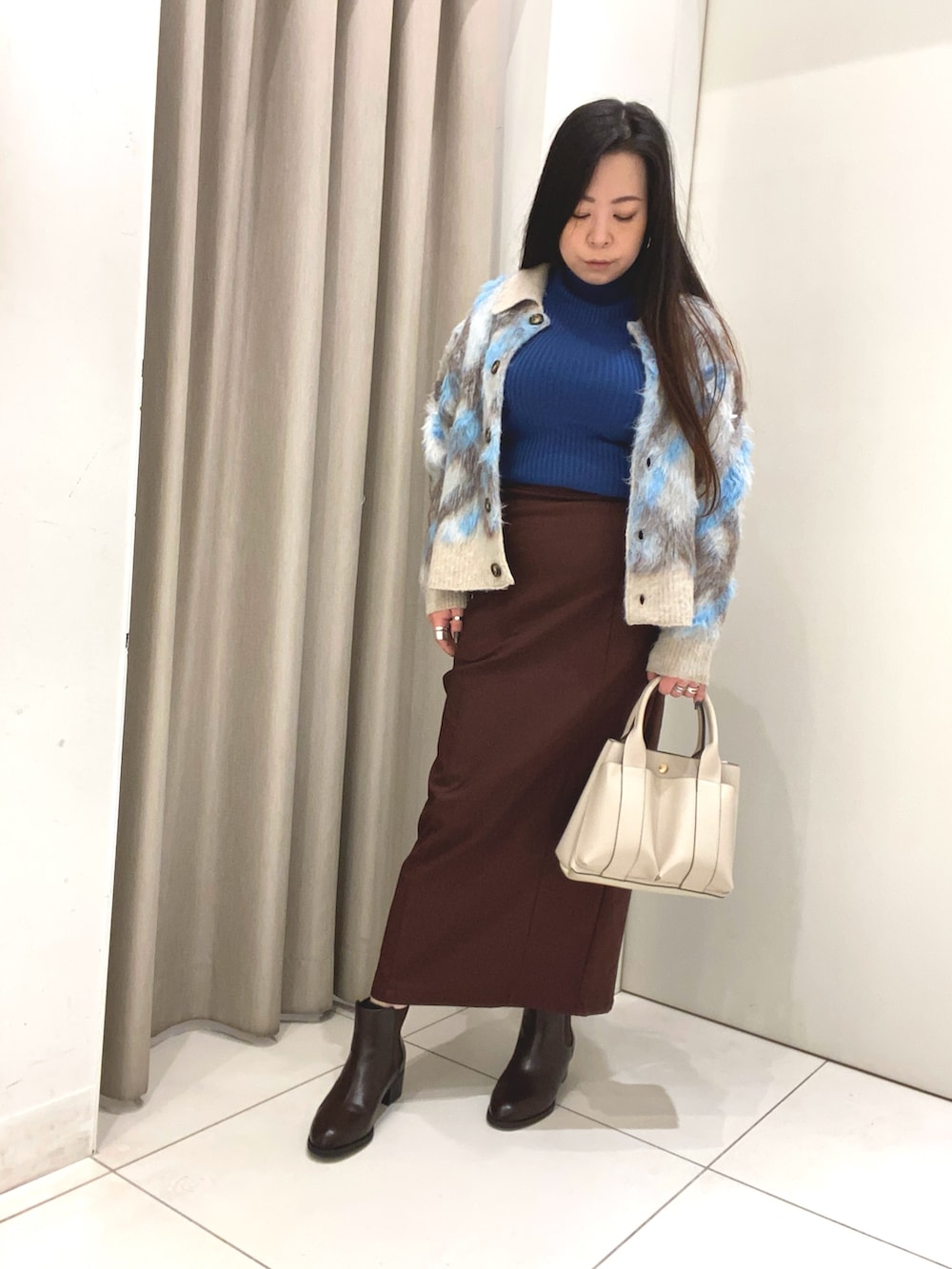 ブルー系のニット/セーター、ブルー系のカーディガン/ボレロ、ブラウン系のスカートを着用したレディースの冬コーディネートの2枚目の写真