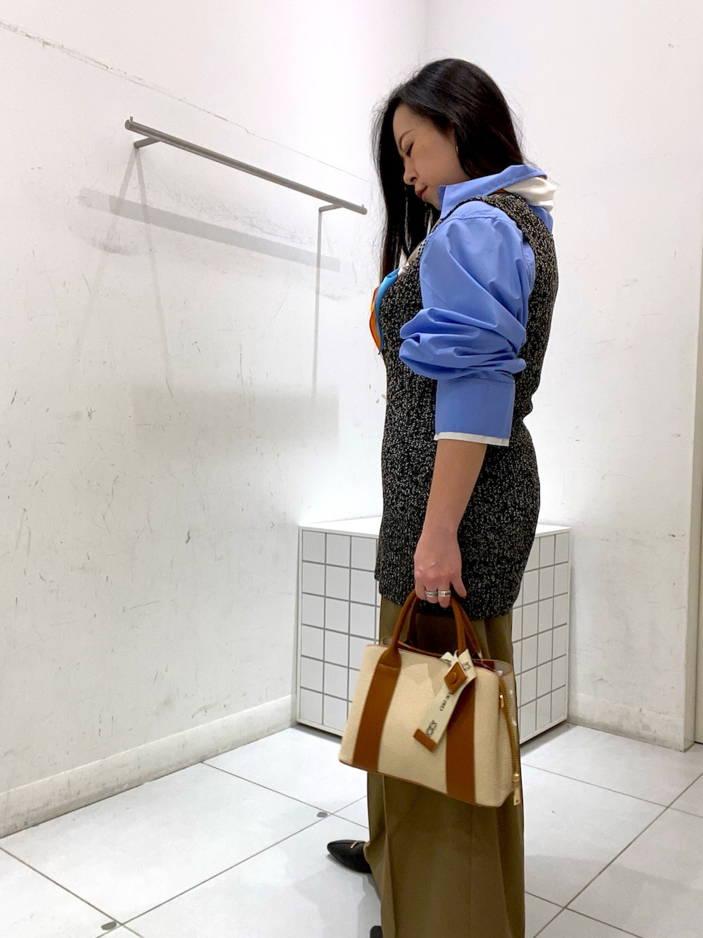 ベージュ系のその他パンツ、ホワイト系のハンドバッグ、ブラック系のベストを着用したレディースの冬コーディネートの2枚目の写真