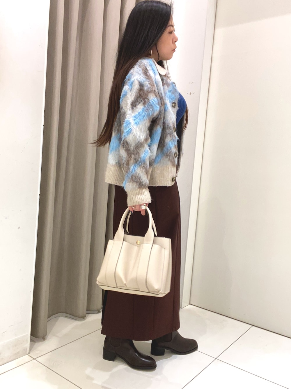 ブルー系のニット/セーター、ブルー系のカーディガン/ボレロ、ブラウン系のスカートを着用したレディースの冬コーディネートの3枚目の写真