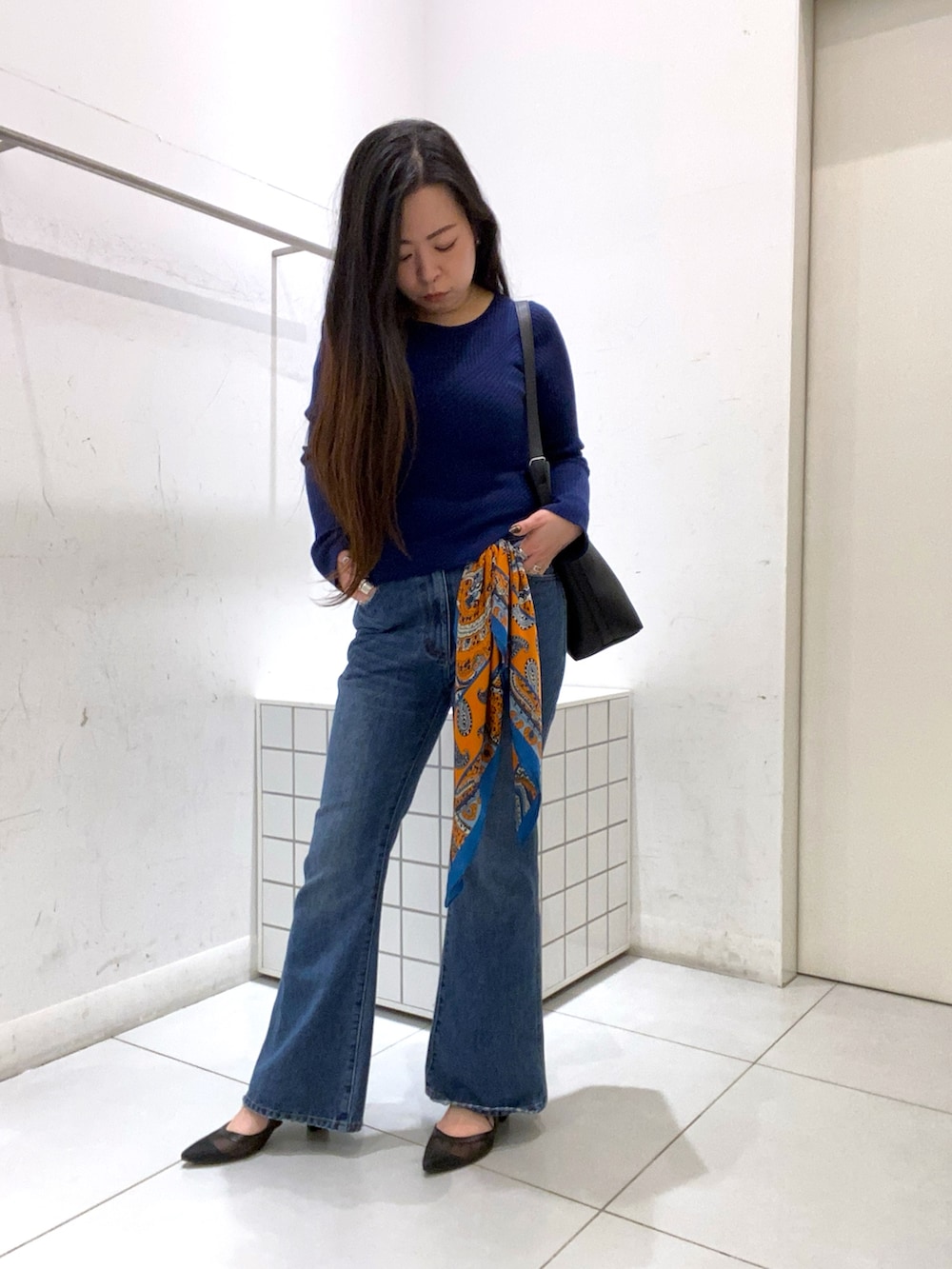 ブルー系のニット/セーター、ブラック系のショルダーバッグ、ブルー系のデニムパンツを着用したレディースの冬コーディネートの2枚目の写真