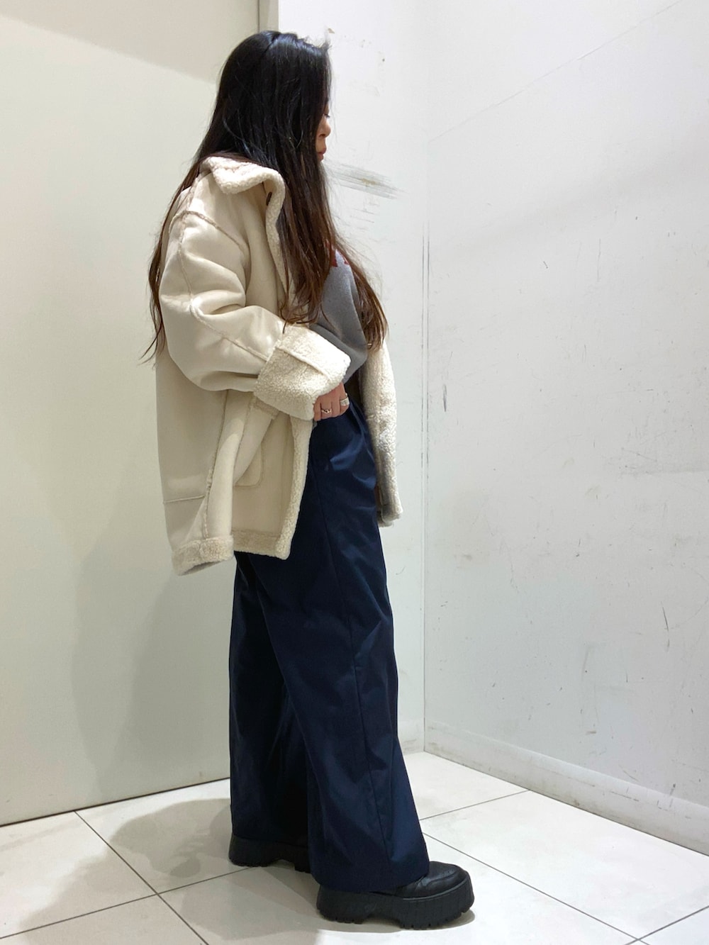 グレー系のニット/セーター、ブルー系のチノパンツ、ホワイト系のムートンコートを着用したレディースの冬コーディネートの2枚目の写真