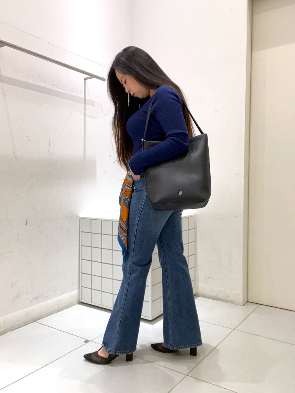 ブルー系のニット/セーター、ブラック系のショルダーバッグ、ブルー系のデニムパンツを着用したレディースの冬コーディネートの3枚目の写真