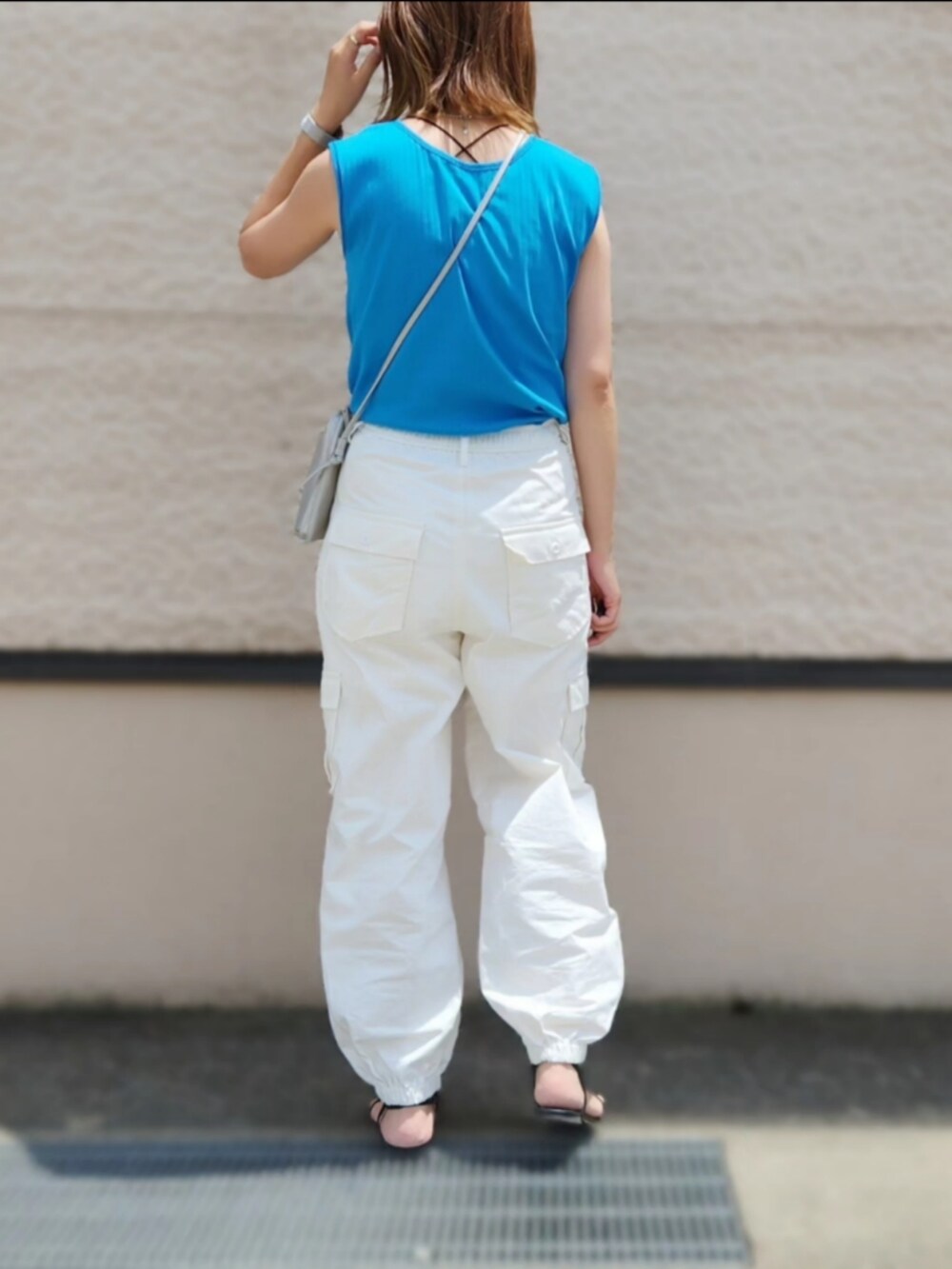 ブルー系のタンクトップ、ホワイト系のカーゴパンツ、ブラック系のサンダルを着用したレディースの夏コーディネートの2枚目の写真
