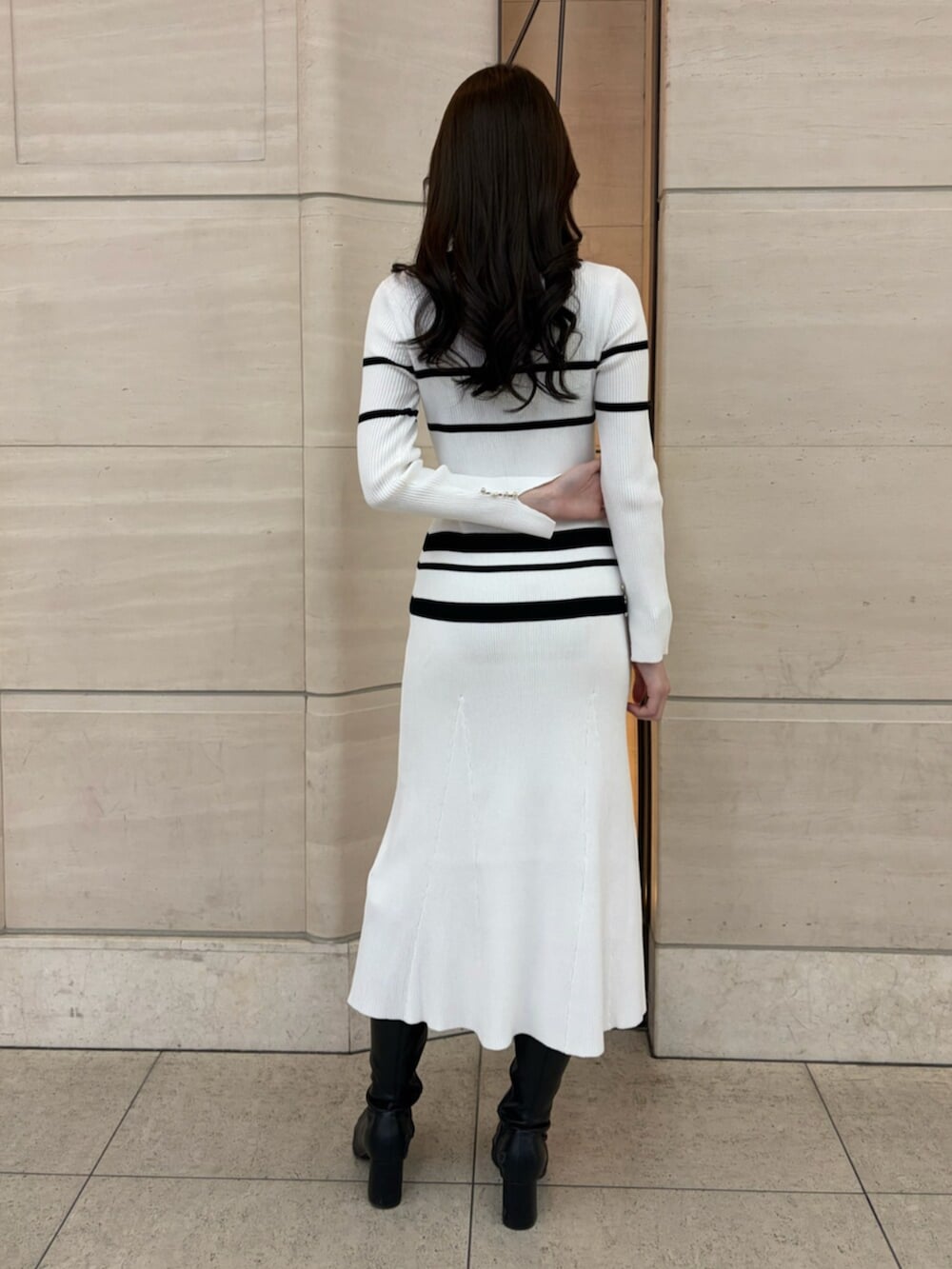 ホワイト系のワンピース、ブラック系のブーツを着用したレディースの冬コーディネートの4枚目の写真