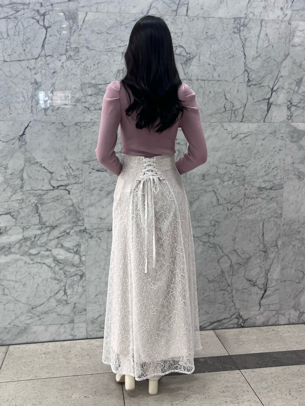 ピンク系のニット/セーター、ホワイト系のスカート、ホワイト系のブーツを着用したレディースの冬コーディネートの3枚目の写真