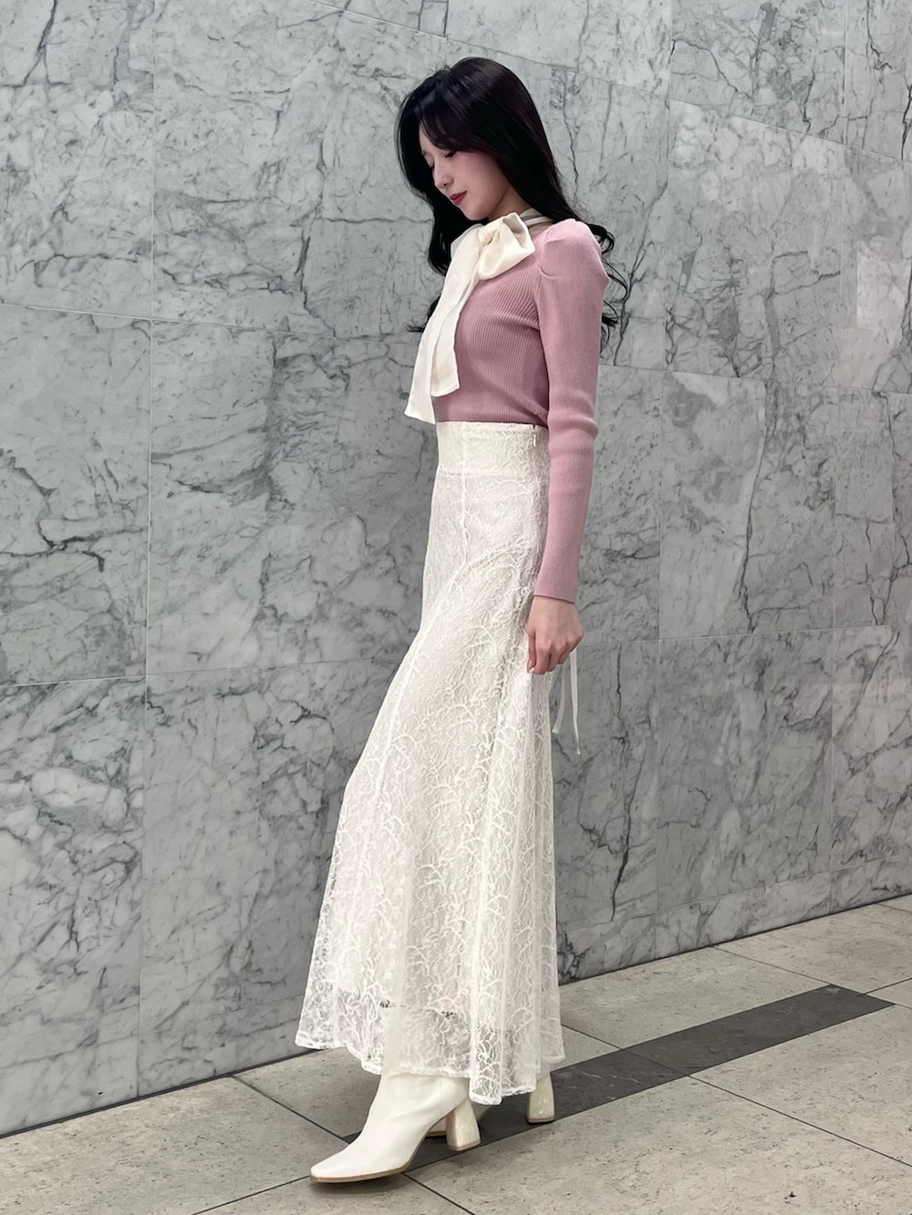 ピンク系のニット/セーター、ホワイト系のスカート、ホワイト系のブーツを着用したレディースの冬コーディネートの2枚目の写真