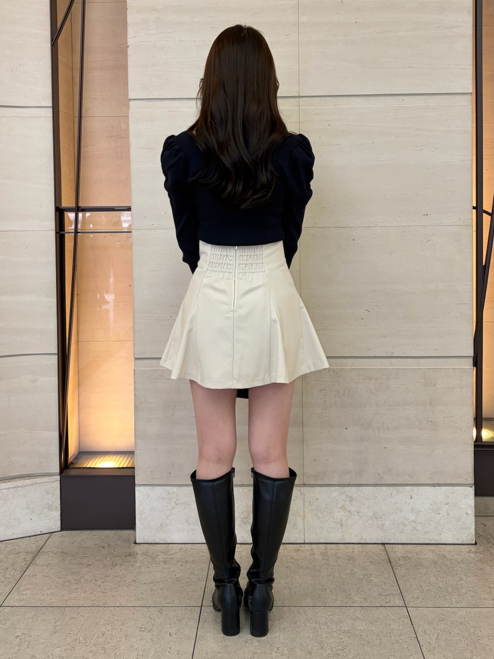 ホワイト系のスカート、ブルー系のニット/セーター、ブラック系のブーツを着用したレディースの冬コーディネートの3枚目の写真