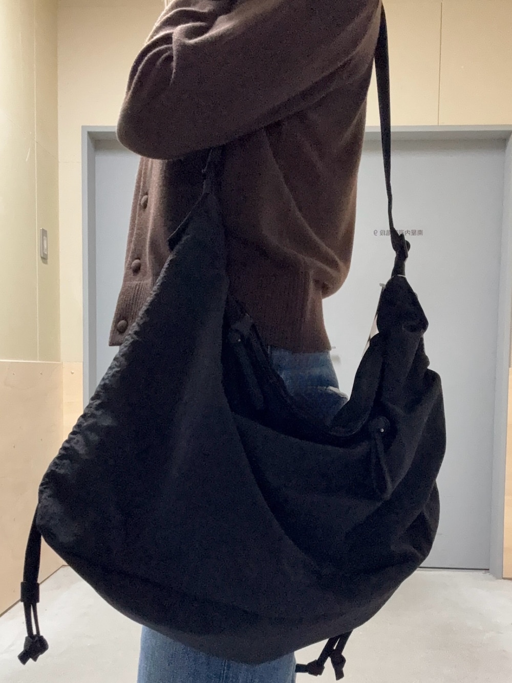 ブラウン系のニット/セーター、ブルー系のデニムパンツ、ブラック系のその他雑貨を着用したレディースの秋コーディネートの3枚目の写真