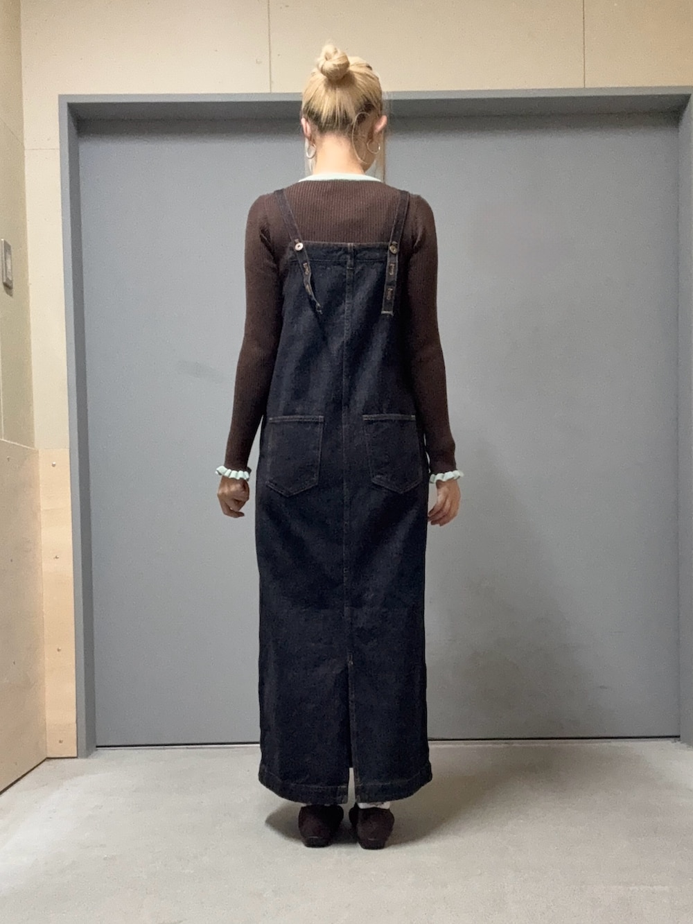 ブラウン系のニット/セーター、ブラック系のジャンパースカート、ブラウン系のスニーカーを着用したレディースの秋コーディネートの3枚目の写真