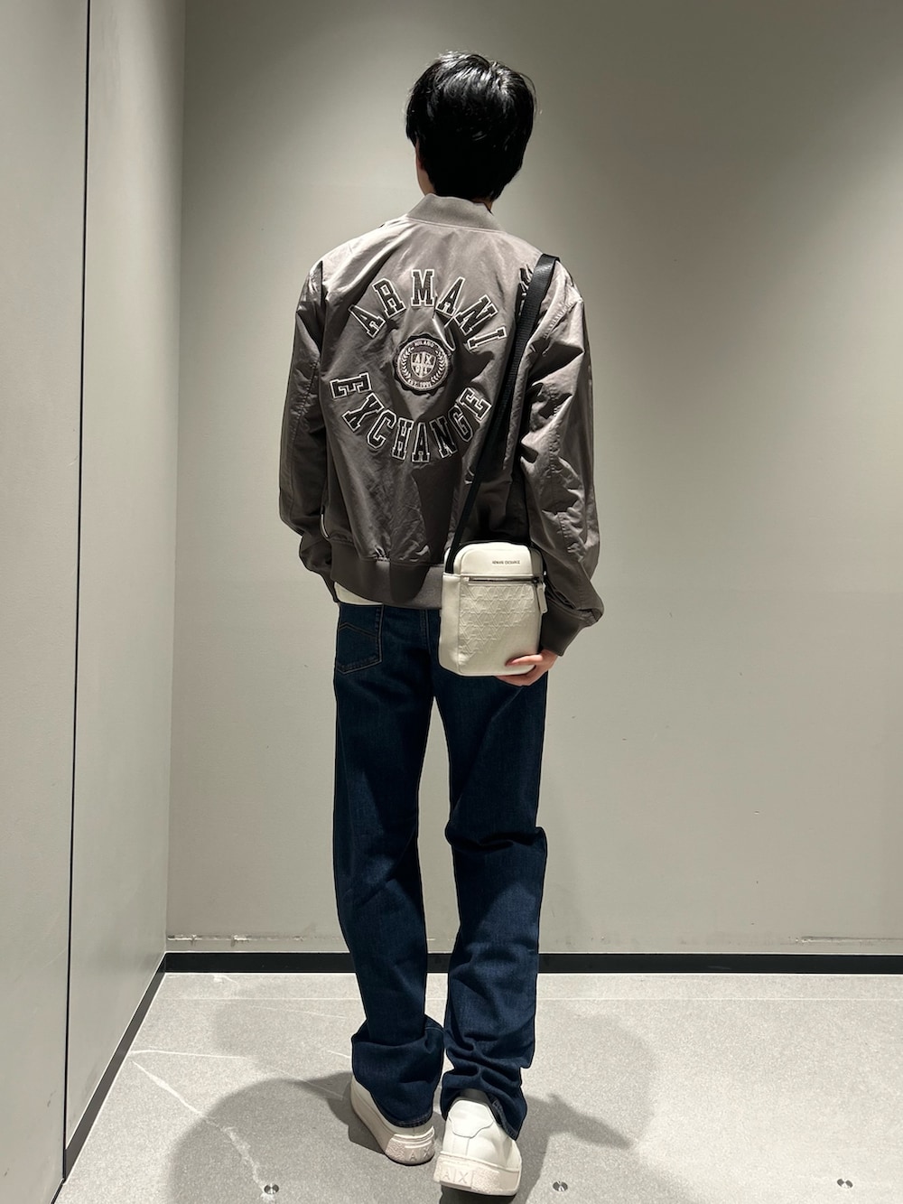 グレー系のブルゾン、ホワイト系のTシャツ/カットソー、ブラック系のショルダーバッグを着用したメンズの秋コーディネートの2枚目の写真