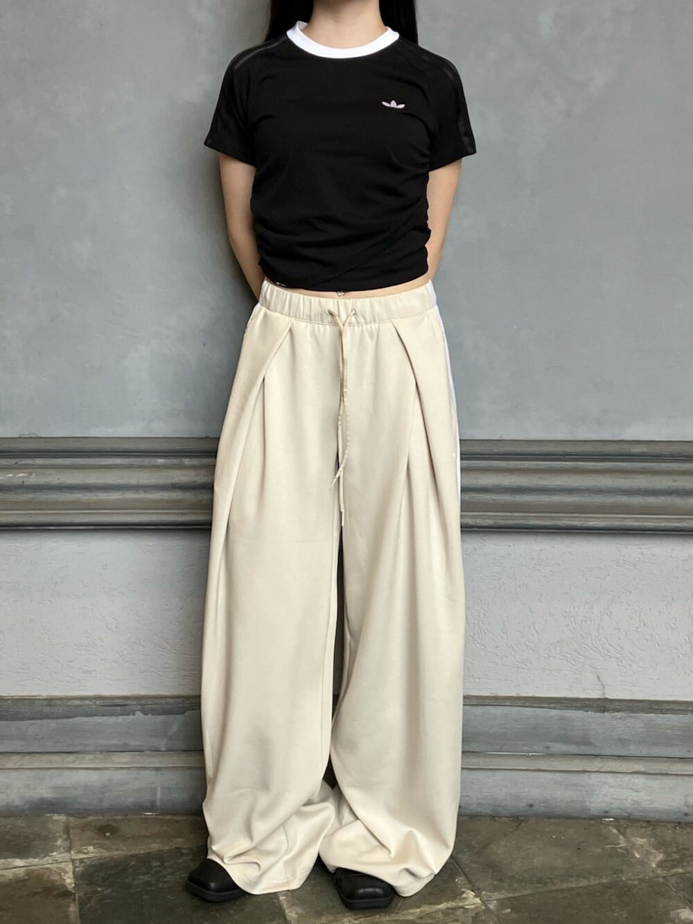 ブラック系のスニーカー、ブラック系のTシャツ/カットソー、ベージュ系のスウェットパンツを着用したレディースの秋コーディネートの3枚目の写真
