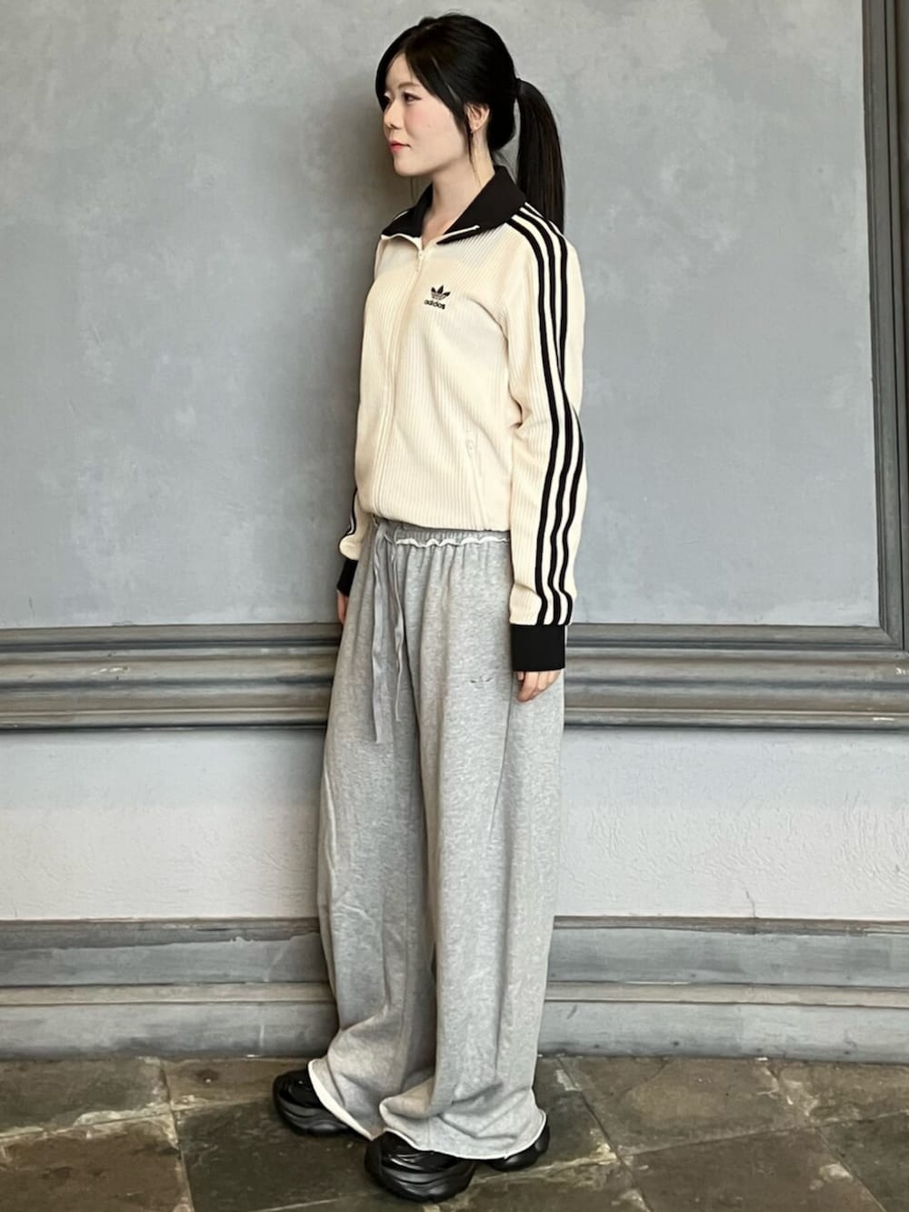 ホワイト系のジャージ、グレー系のパンツ、ブラック系のスニーカーを着用したレディースの秋コーディネートの2枚目の写真