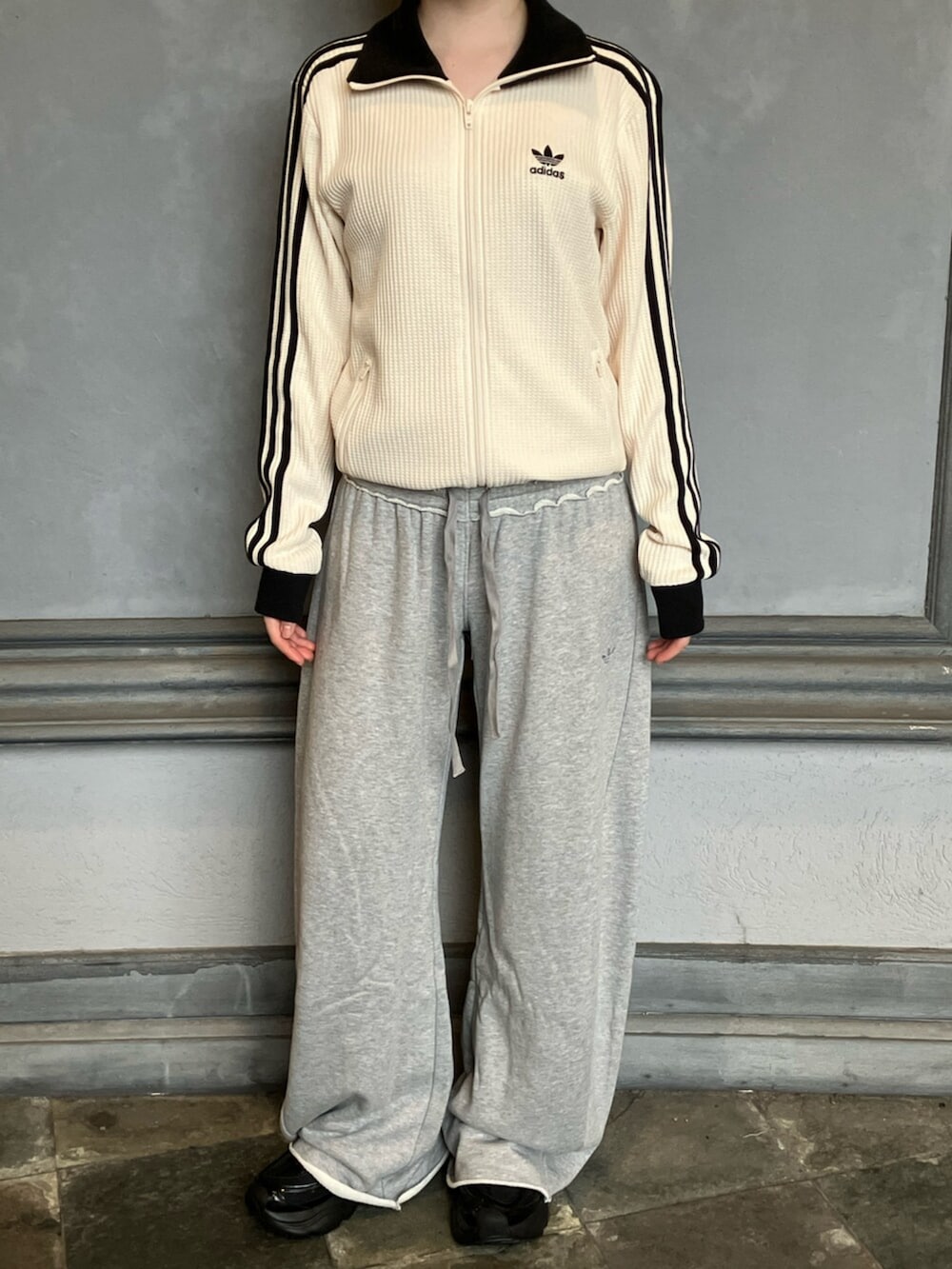 ホワイト系のジャージ、グレー系のパンツ、ブラック系のスニーカーを着用したレディースの秋コーディネートの3枚目の写真