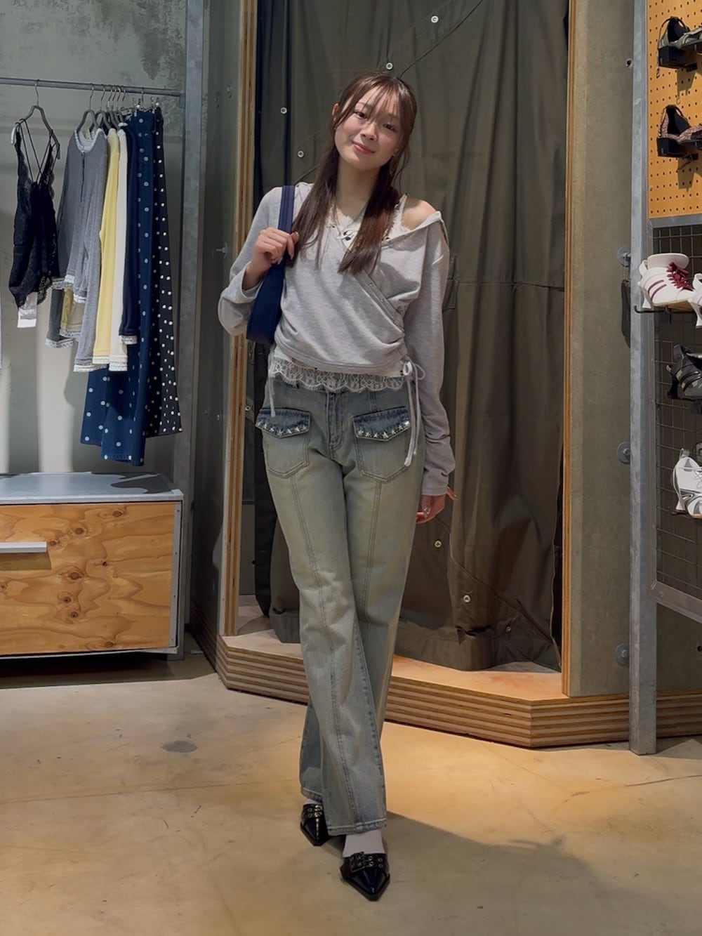 グレー系のパーカー、ホワイト系のキャミソール、ブルー系のデニムパンツを着用したレディースの春コーディネートの2枚目の写真