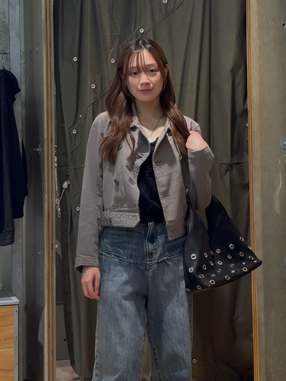 グレー系のピーコート、ブルー系のデニムパンツ、ブラック系のショルダーバッグを着用したレディースの春コーディネートの2枚目の写真