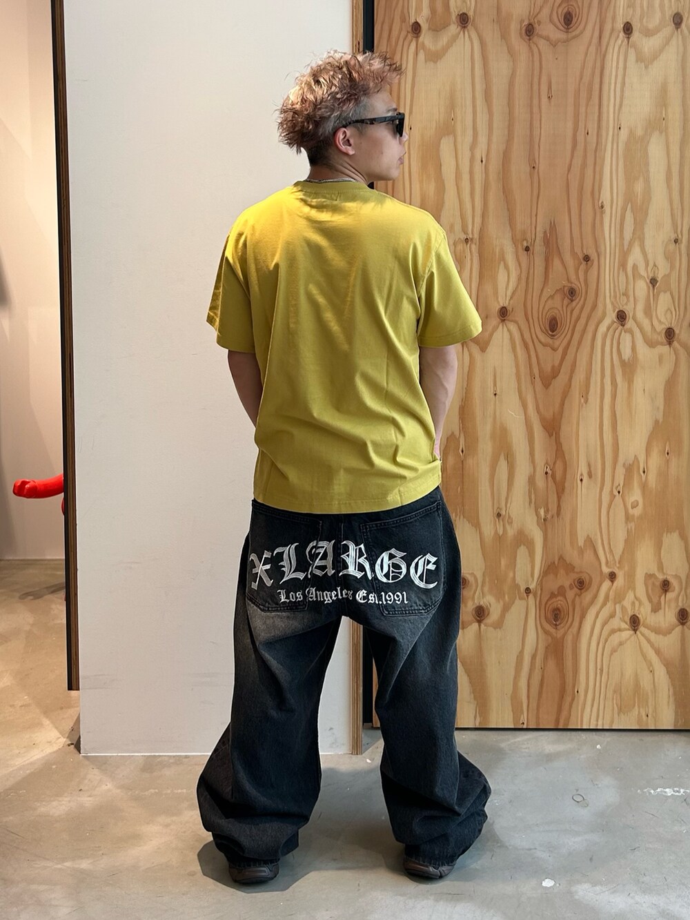 イエロー系のTシャツ/カットソー、ブラック系のデニムパンツ、ブラウン系のサングラスを着用したメンズの夏コーディネートの2枚目の写真