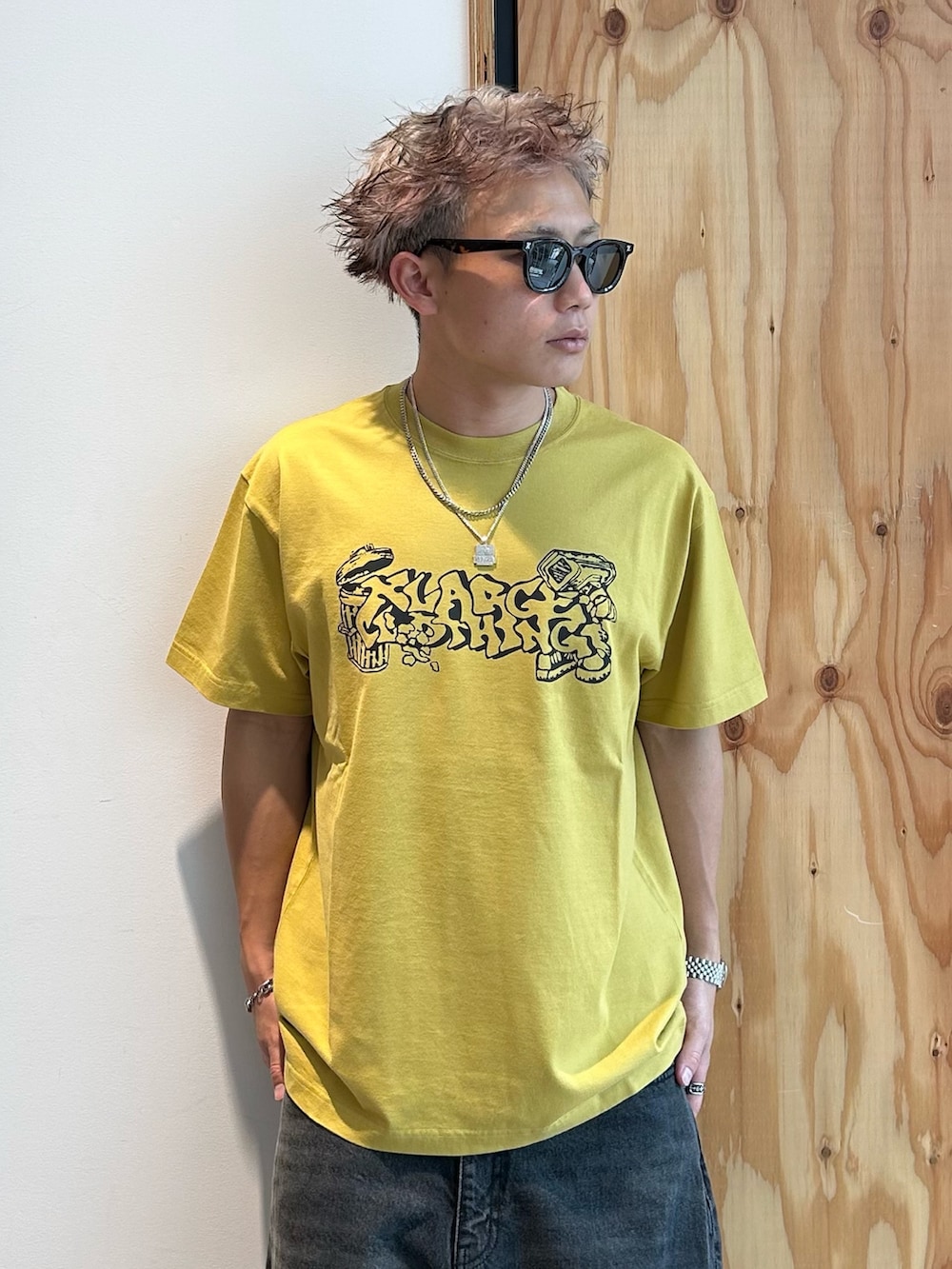 イエロー系のTシャツ/カットソー、ブラック系のデニムパンツ、ブラウン系のサングラスを着用したメンズの夏コーディネートの3枚目の写真
