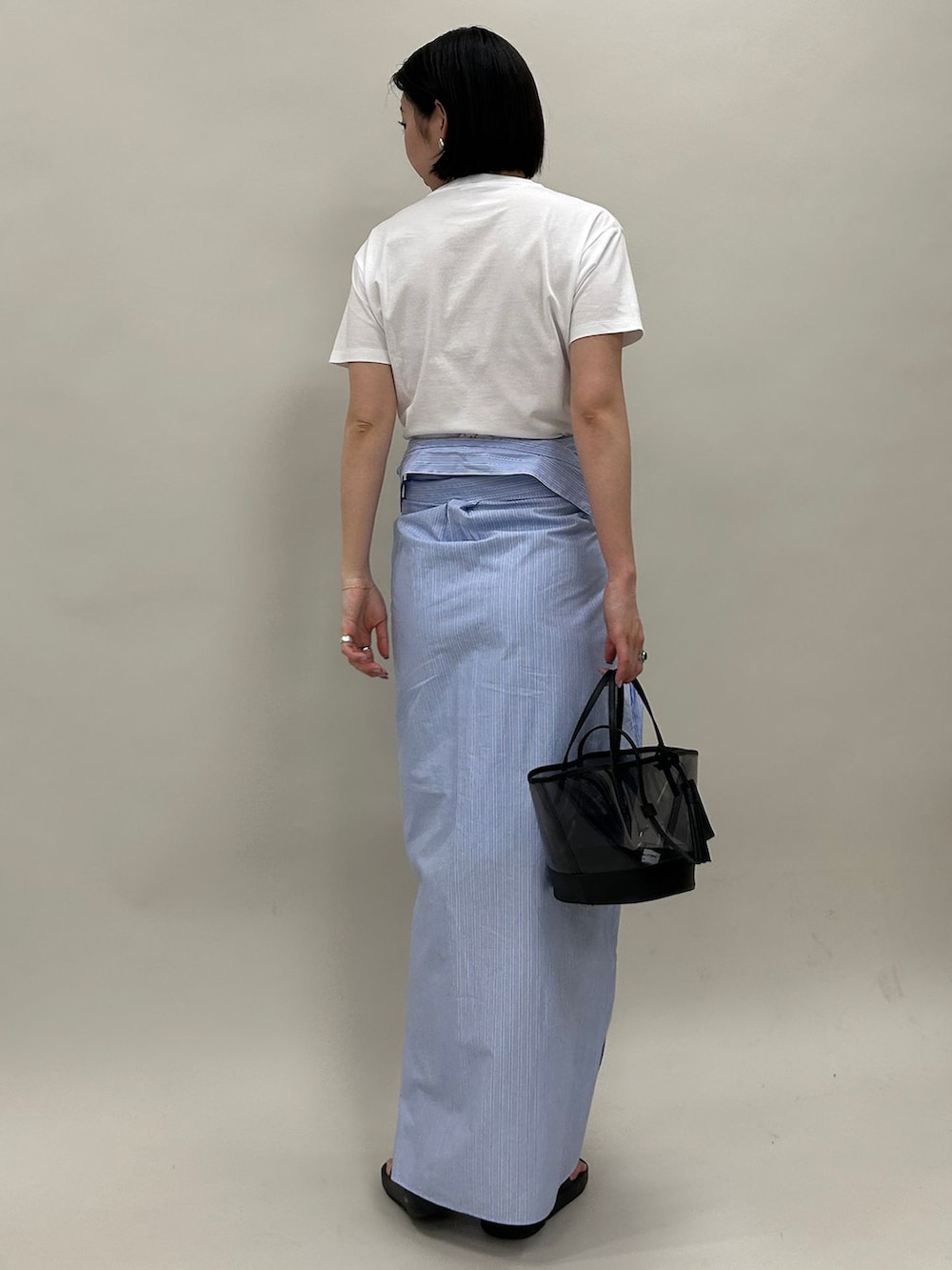 ブルー系のシャツワンピース、ホワイト系のTシャツ/カットソー、ブラック系のハンドバッグを着用したレディースの春コーディネートの3枚目の写真
