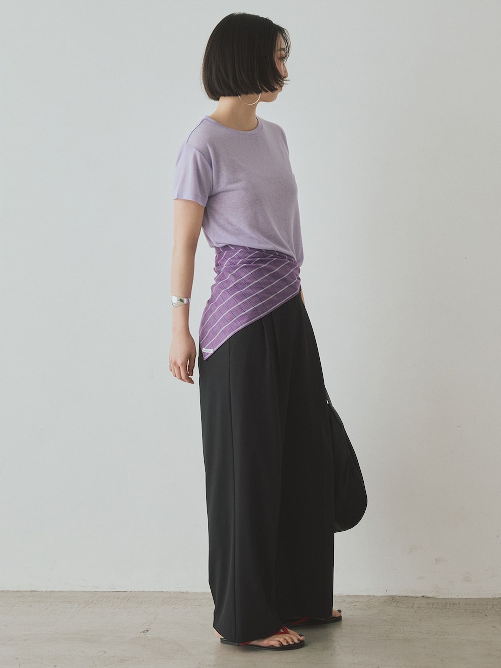 ブラック系のスラックス、パープル系のTシャツ/カットソー、ブラック系のトートバッグを着用したレディースの夏コーディネートの3枚目の写真