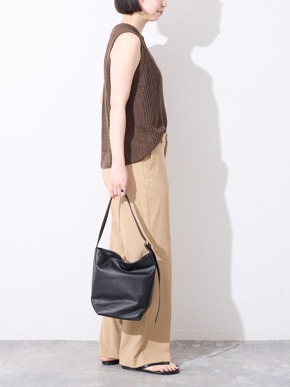 ベージュ系のその他パンツ、ブラウン系のニット/セーター、ブラック系のサンダルを着用したレディースの春コーディネートの3枚目の写真