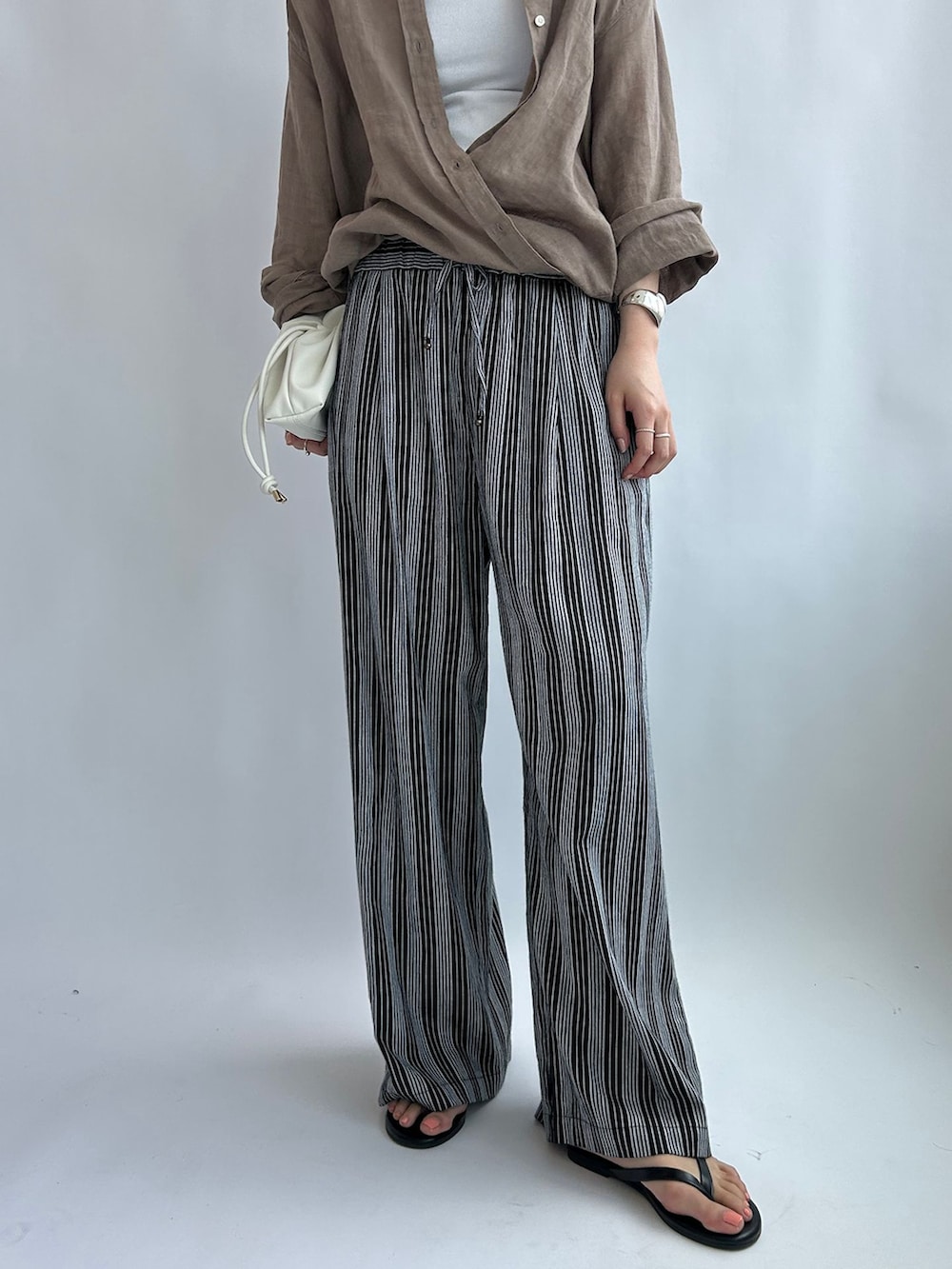 ブラック系のその他パンツ、ベージュ系のシャツ/ブラウス、ホワイト系のタンクトップを着用したレディースの夏コーディネートの6枚目の写真