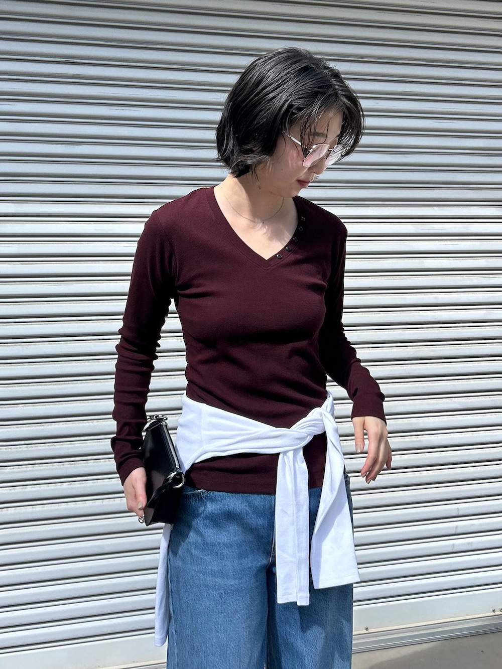 ブルー系のデニムパンツ、レッド系のTシャツ/カットソー、ブラック系のハンドバッグを着用したレディースの夏コーディネートの3枚目の写真