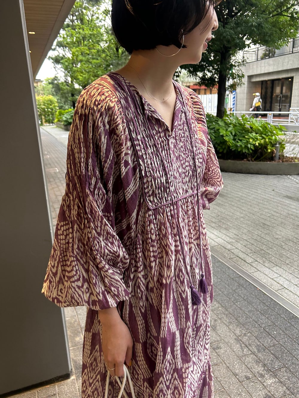ブルー系のデニムパンツ、パープル系のワンピース、ホワイト系のクラッチバッグを着用したレディースの夏コーディネートの5枚目の写真
