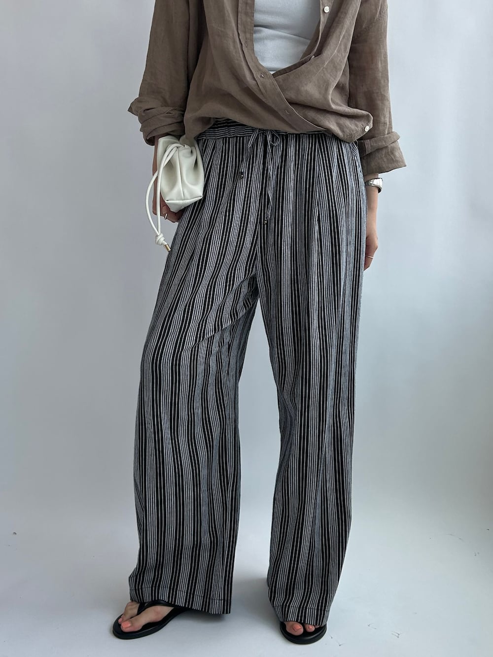 ブラック系のその他パンツ、ベージュ系のシャツ/ブラウス、ホワイト系のタンクトップを着用したレディースの夏コーディネートの5枚目の写真