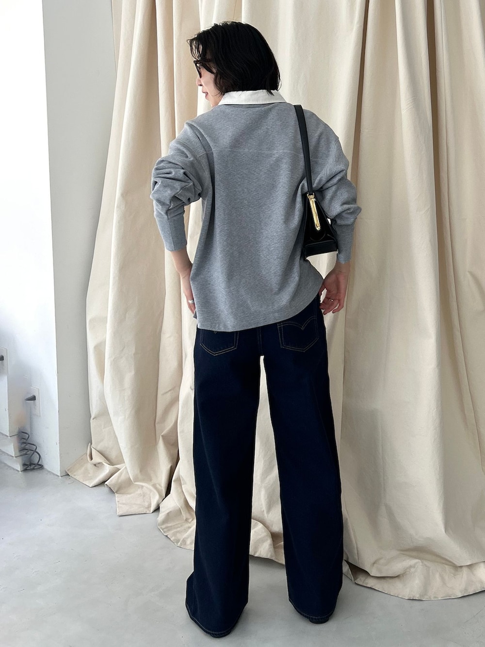 ブルー系のデニムパンツ、グレー系のTシャツ/カットソー、ブラック系のショルダーバッグを着用したレディースの夏コーディネートの3枚目の写真