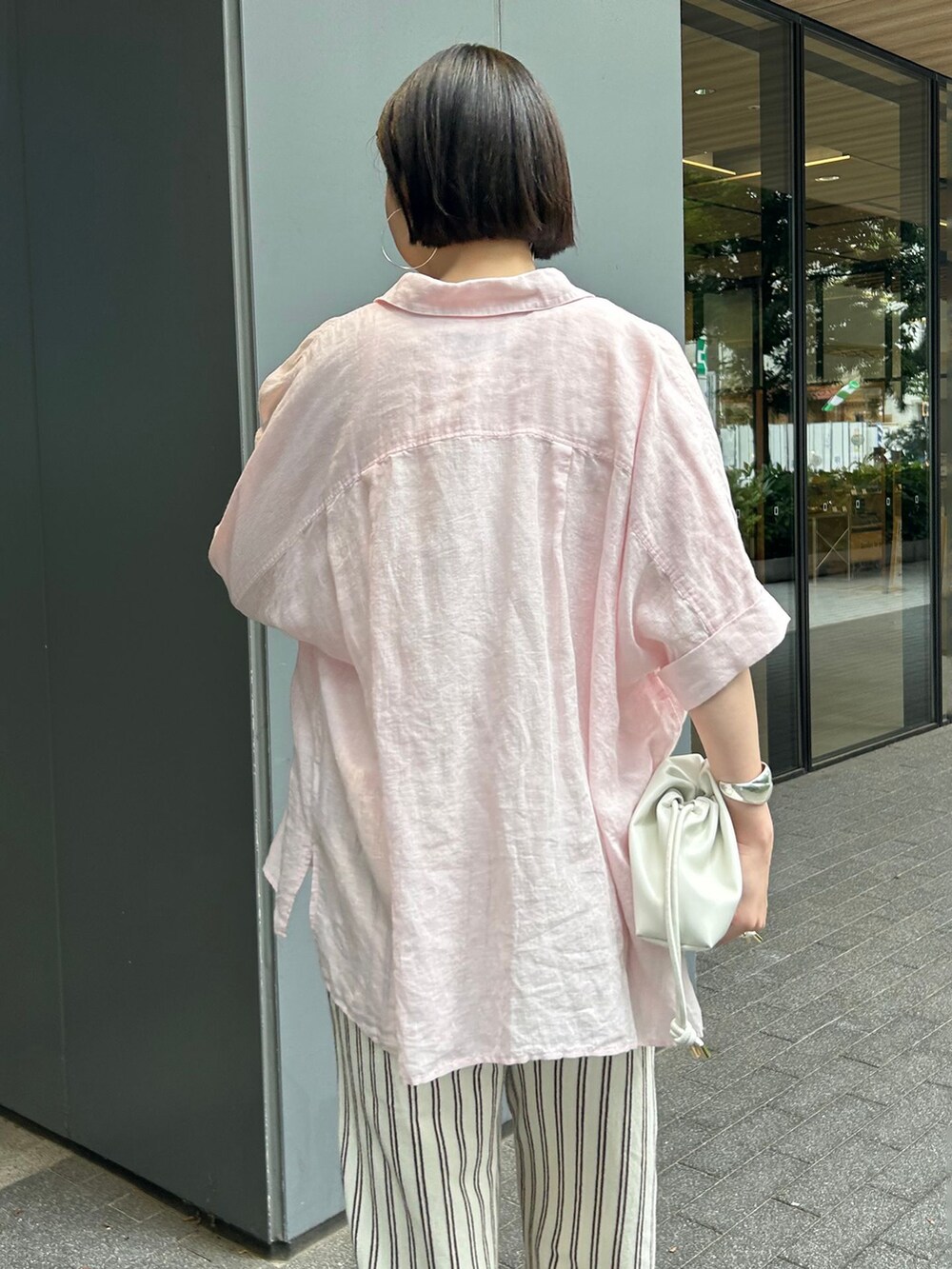 ホワイト系のタンクトップ、ピンク系のシャツ/ブラウス、ホワイト系のクラッチバッグを着用したレディースの夏コーディネートの6枚目の写真