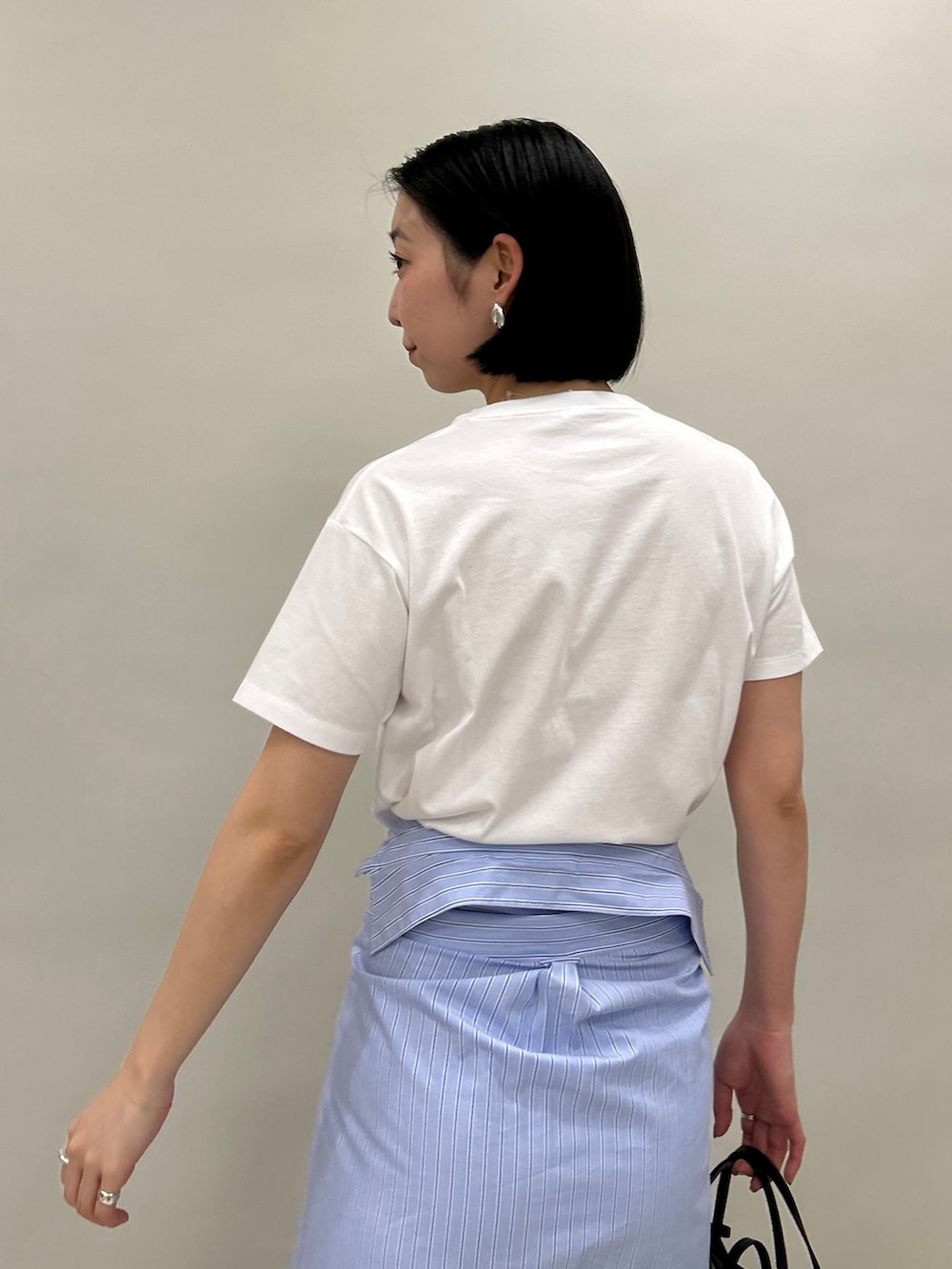 ブルー系のシャツワンピース、ホワイト系のTシャツ/カットソー、ブラック系のハンドバッグを着用したレディースの春コーディネートの6枚目の写真