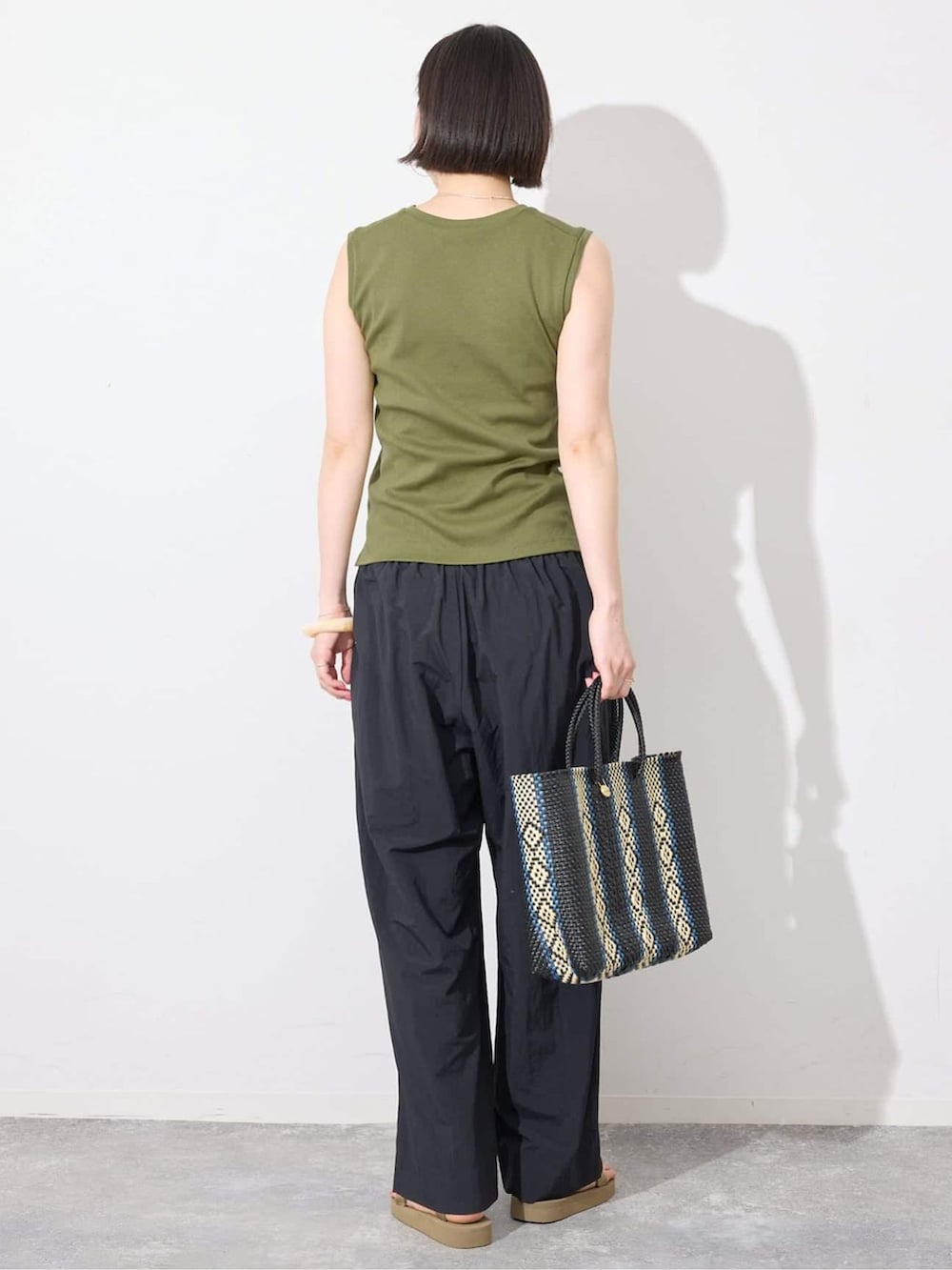ブラック系のその他パンツ、グリーン系のTシャツ/カットソー、ブルー系のトートバッグを着用したレディースの夏コーディネートの3枚目の写真