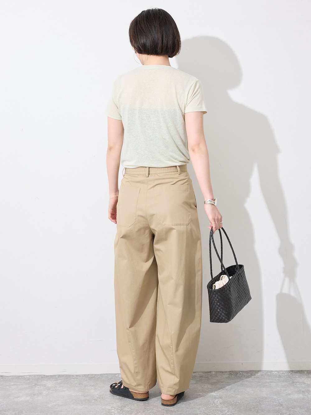 ベージュ系のチノパンツ、グリーン系のTシャツ/カットソー、ブラック系のかごバッグを着用したレディースの夏コーディネートの3枚目の写真