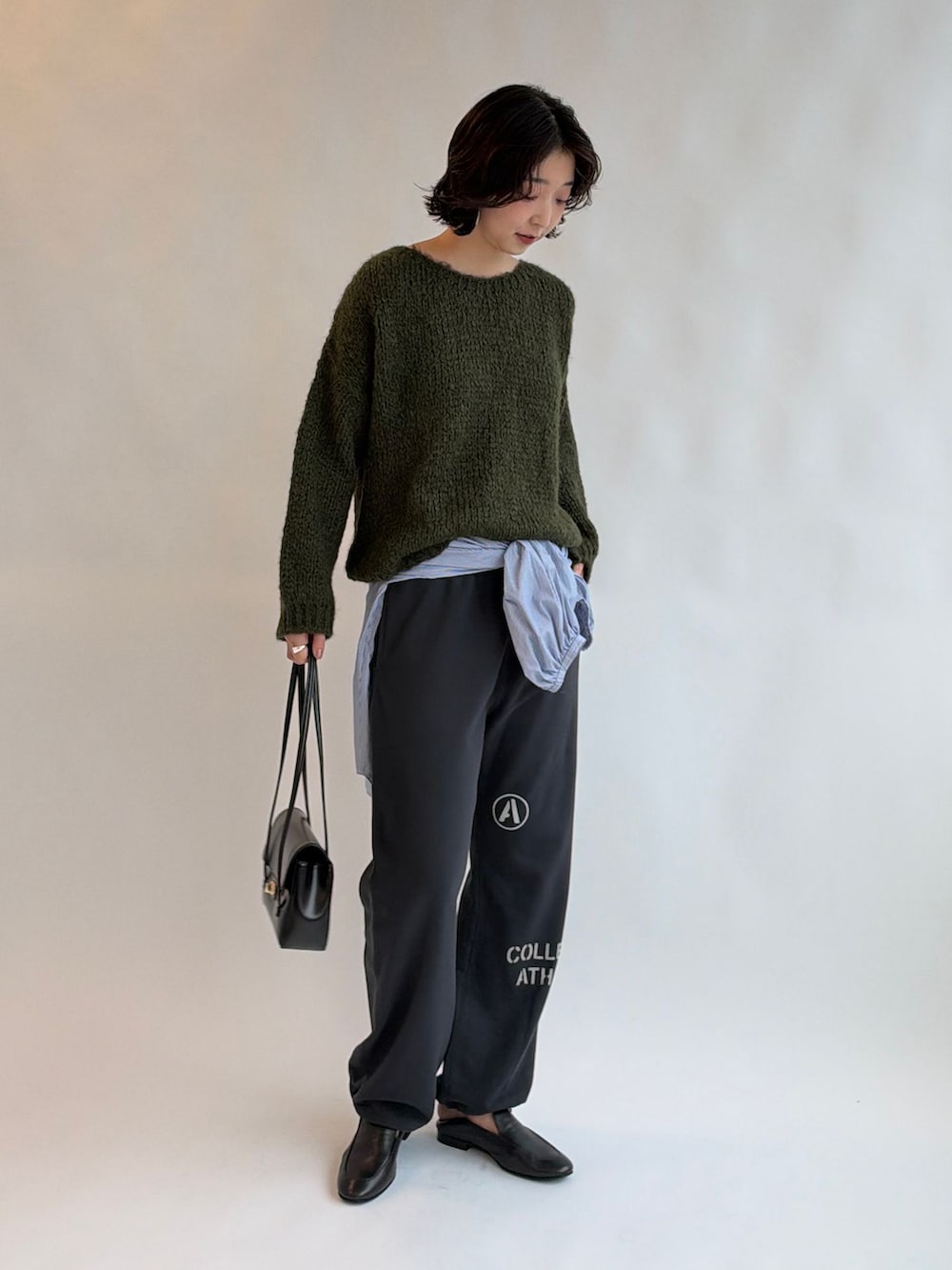 ブルー系のシャツ/ブラウス、グリーン系のニット/セーター、ブラック系のショルダーバッグを着用したレディースの秋コーディネートの2枚目の写真