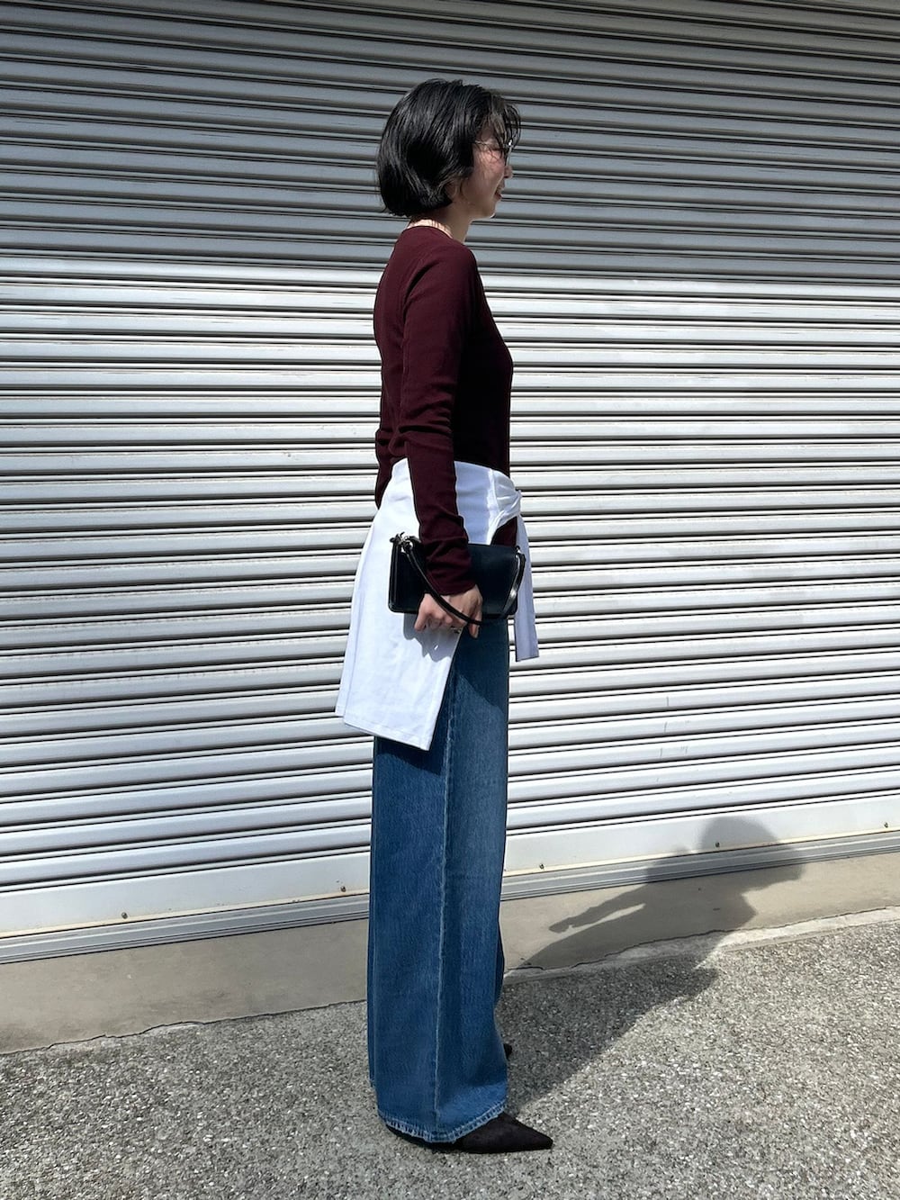 ブルー系のデニムパンツ、レッド系のTシャツ/カットソー、ブラック系のハンドバッグを着用したレディースの夏コーディネートの2枚目の写真