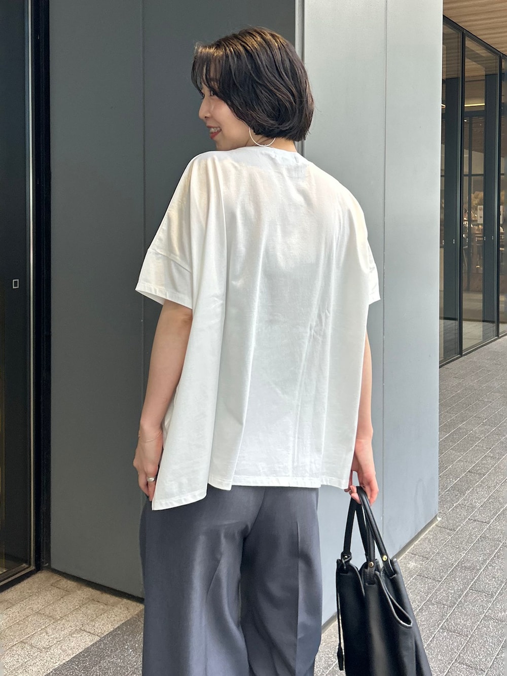 グレー系のスラックス、ブラック系のトートバッグ、ブラック系のサンダルを着用したレディースの夏コーディネートの6枚目の写真