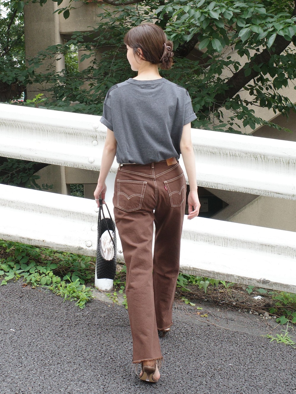 ブラウン系のデニムパンツ、グレー系のTシャツ/カットソー、ブラック系のかごバッグを着用したレディースの夏コーディネートの3枚目の写真