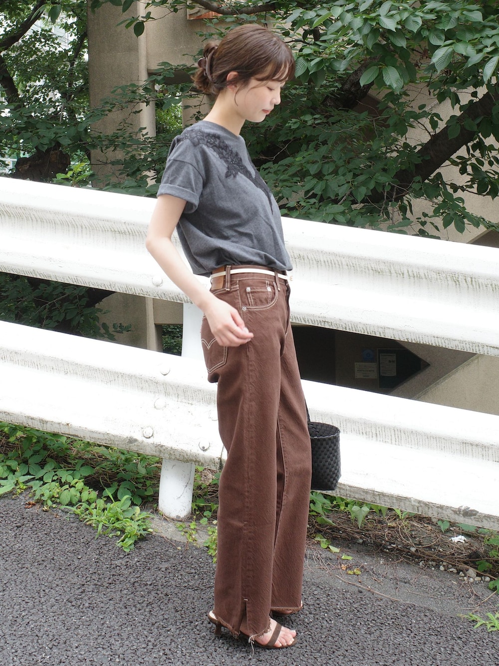 ブラウン系のデニムパンツ、グレー系のTシャツ/カットソー、ブラック系のかごバッグを着用したレディースの夏コーディネートの2枚目の写真