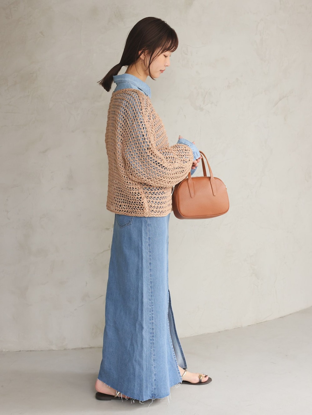 ブルー系のシャツ/ブラウス、ブルー系のデニムスカート、ベージュ系のニット/セーターを着用したレディースの冬コーディネートの2枚目の写真