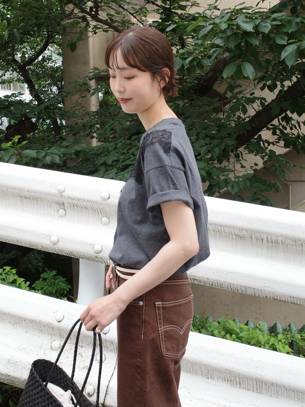 ブラウン系のデニムパンツ、グレー系のTシャツ/カットソー、ブラック系のかごバッグを着用したレディースの夏コーディネートの10枚目の写真