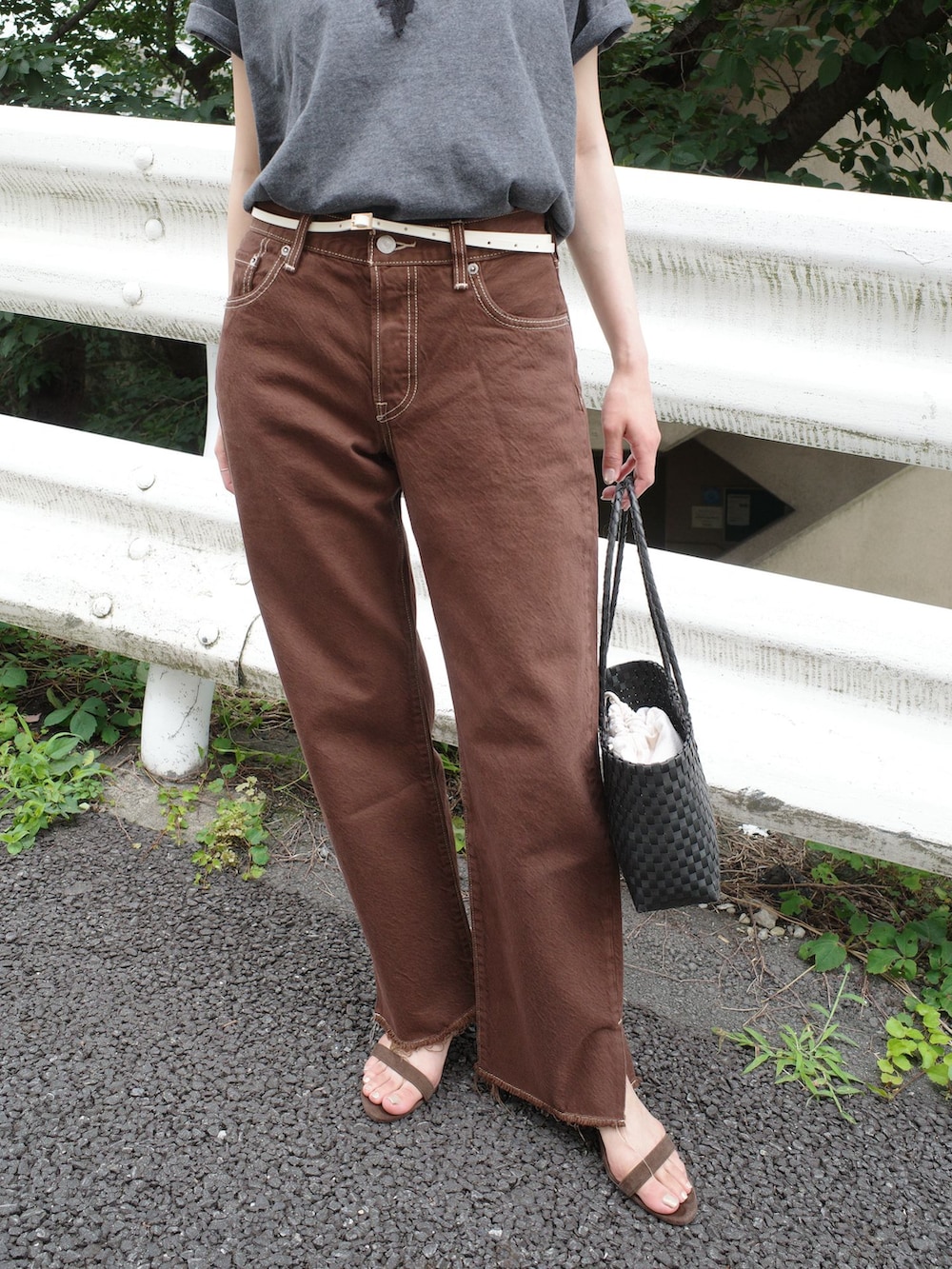 ブラウン系のデニムパンツ、グレー系のTシャツ/カットソー、ブラック系のかごバッグを着用したレディースの夏コーディネートの4枚目の写真
