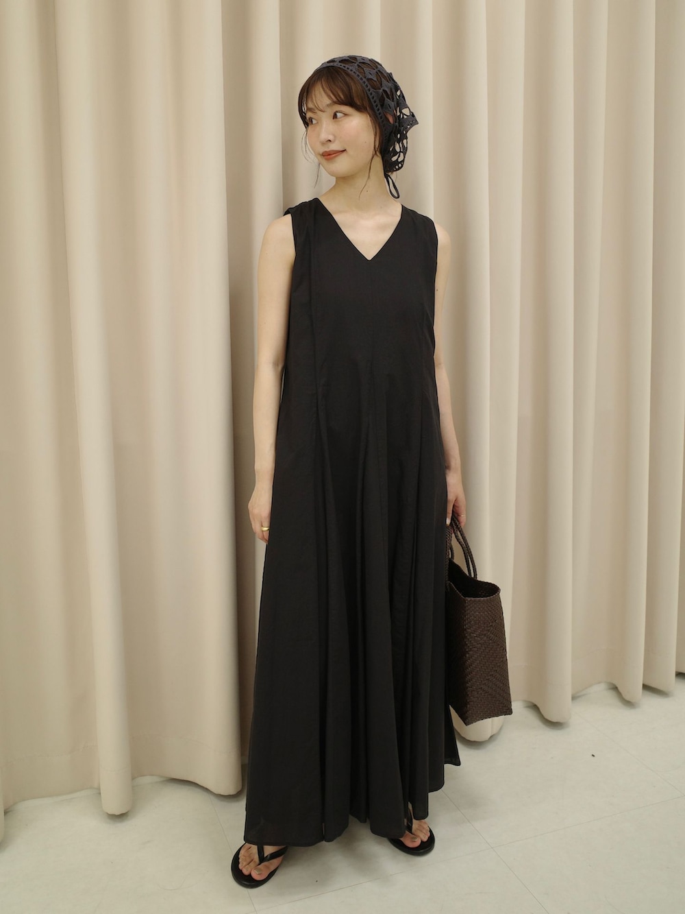 ブラック系のワンピース、ブラウン系のトートバッグ、ブラック系のサンダルを着用したレディースの夏コーディネートの2枚目の写真