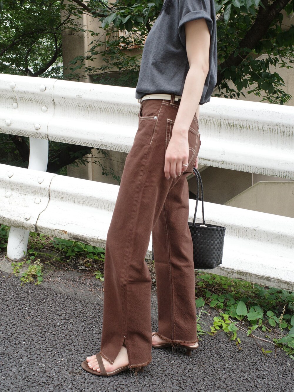 ブラウン系のデニムパンツ、グレー系のTシャツ/カットソー、ブラック系のかごバッグを着用したレディースの夏コーディネートの5枚目の写真