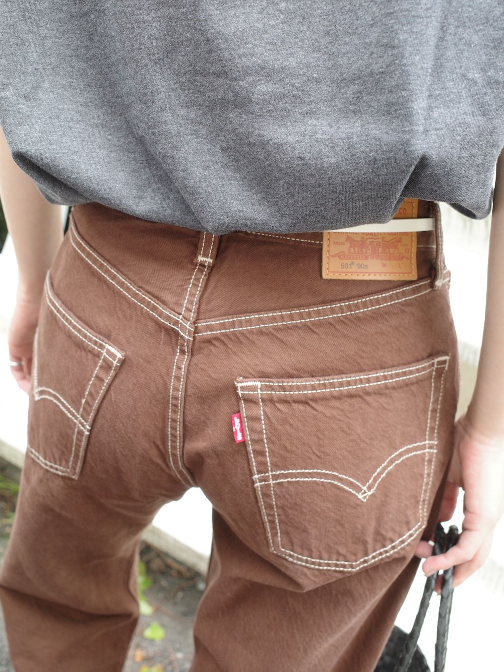 ブラウン系のデニムパンツ、グレー系のTシャツ/カットソー、ブラック系のかごバッグを着用したレディースの夏コーディネートの8枚目の写真