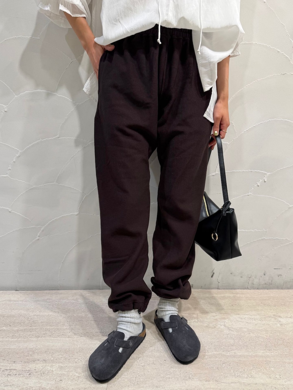 ブラウン系のスウェットパンツ、ホワイト系のシャツ/ブラウス、ブラック系のハンドバッグを着用したレディースの秋コーディネートの6枚目の写真
