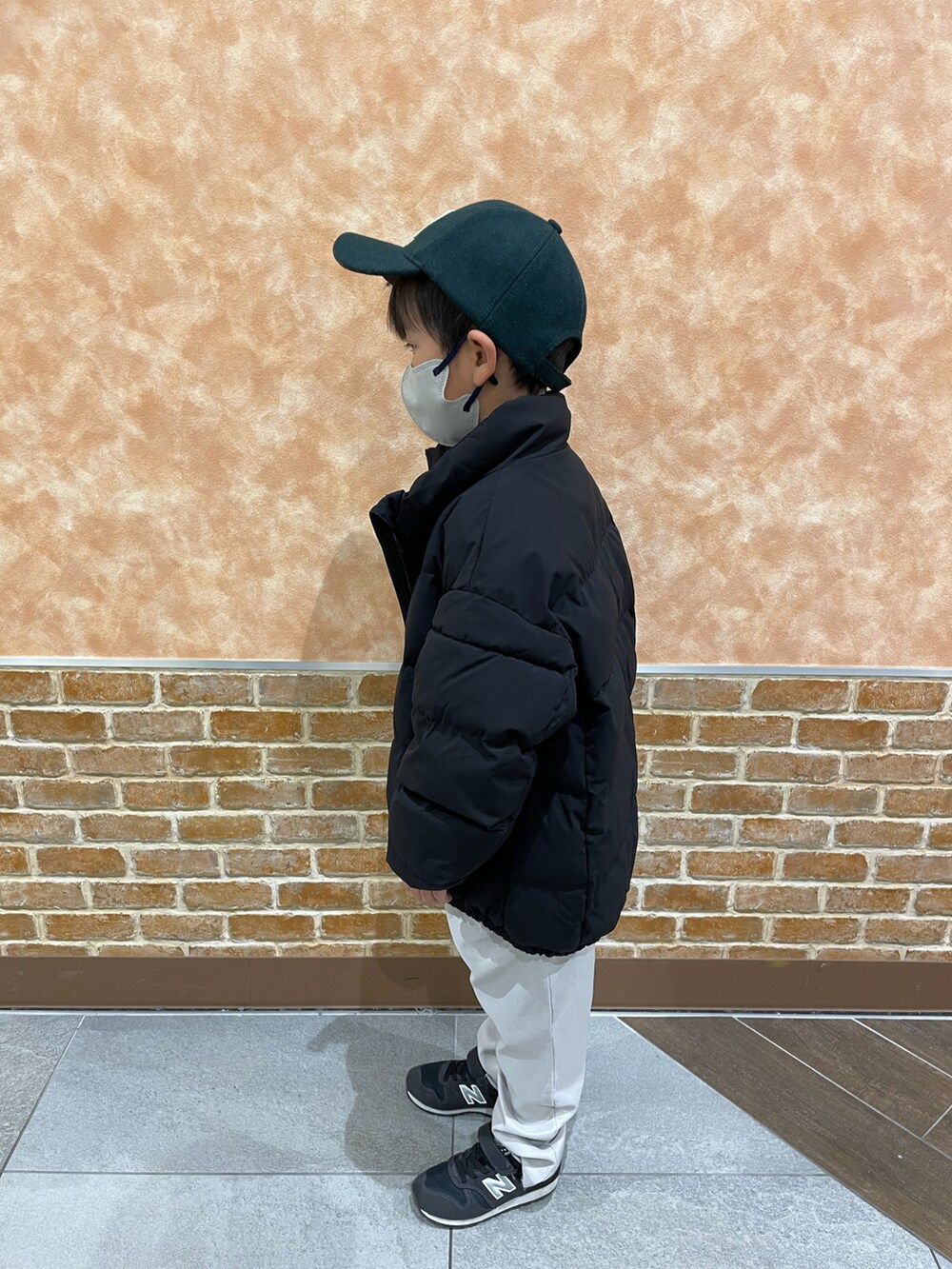 グレー系のパンツ、ブラック系のスニーカー、ブルー系のトップスを着用したキッズの冬コーディネートの2枚目の写真