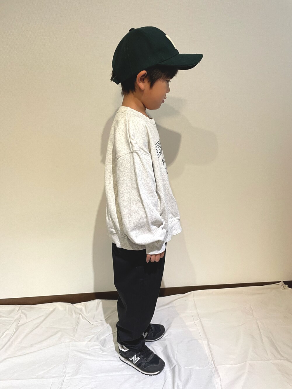 ホワイト系のスウェット、ブラック系のチノパンツ、ブラック系のスニーカーを着用したキッズの秋コーディネートの3枚目の写真