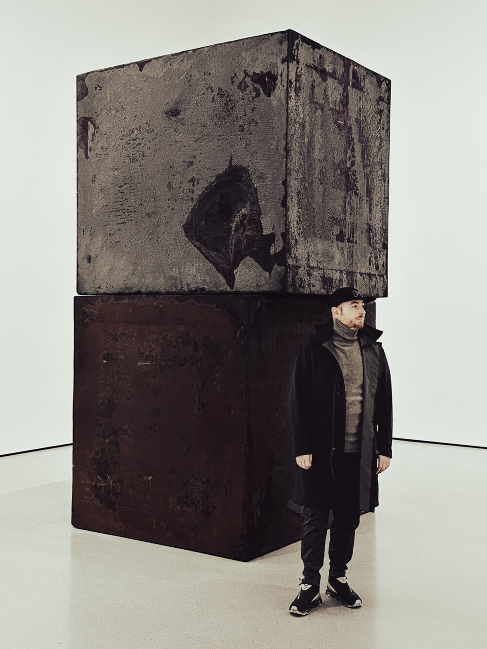 グレー系のトレンチコート、グレー系のカーゴパンツ、ブラック系のスニーカーを着用したメンズの秋コーディネートの2枚目の写真